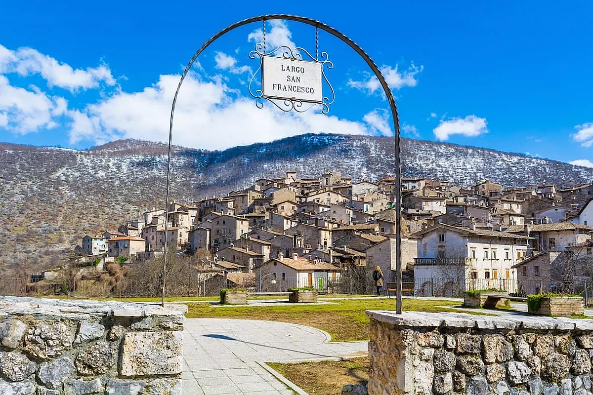 Vista sul paese di Scanno attraverso un arco al quale è appesa una targa su cui c'è scritto 